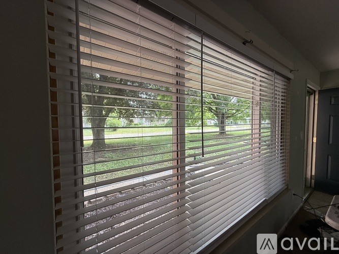 A room with a window covered by white blinds.