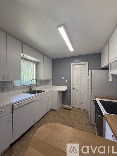 A kitchen with white cabinets and a wooden table.
