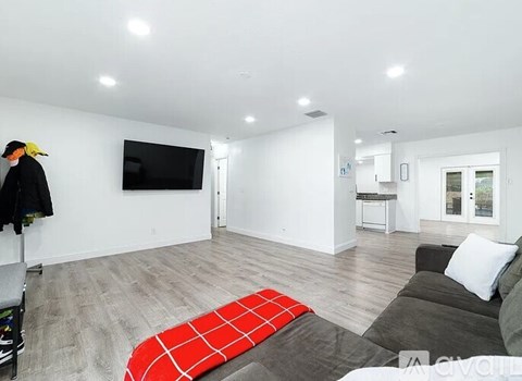 A living room with a grey couch and a red and black rug.