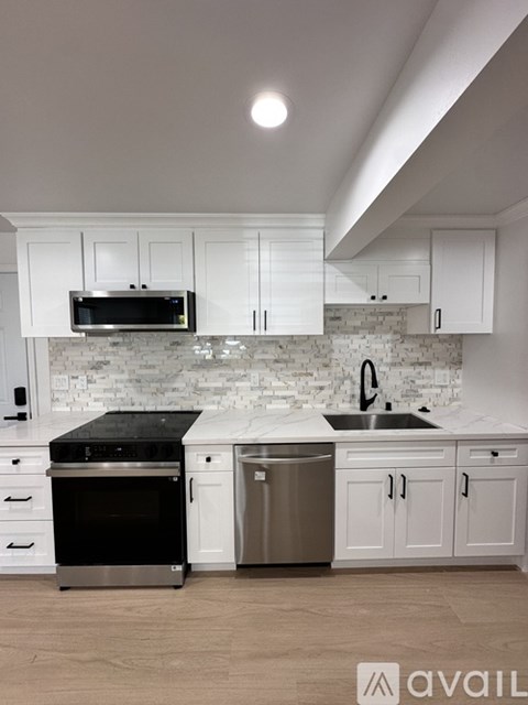 A kitchen with white cabinets and a black stove top oven.