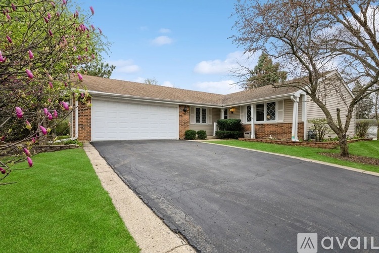 A house with a driveway and a tree with pink flowers.