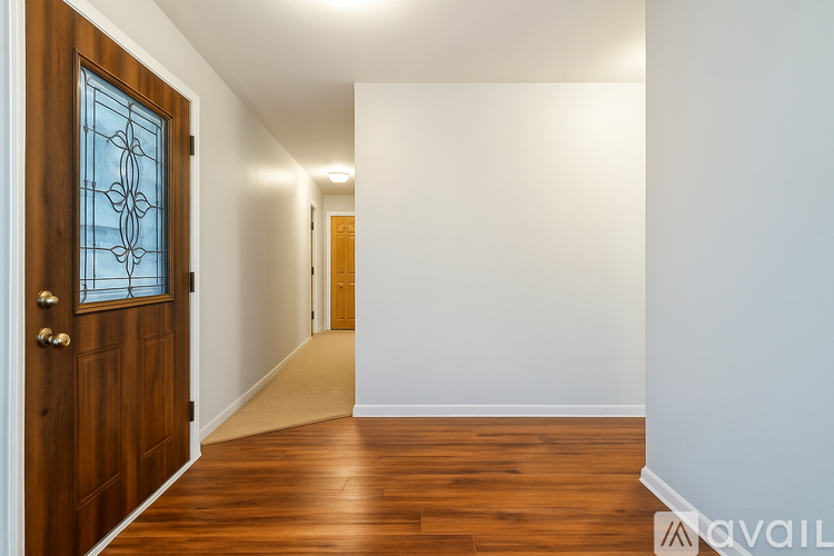 A hallway with a wooden door and a carpeted floor.