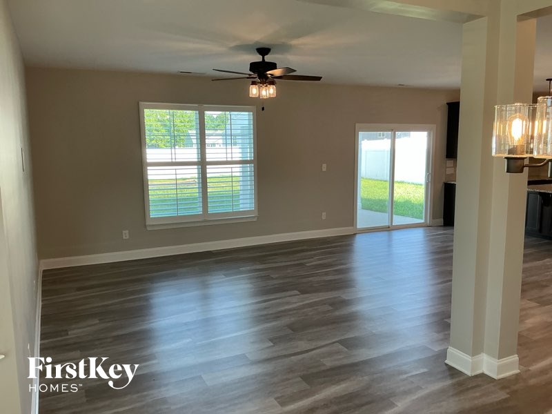 A spacious room with a ceiling fan and lighting fixture.