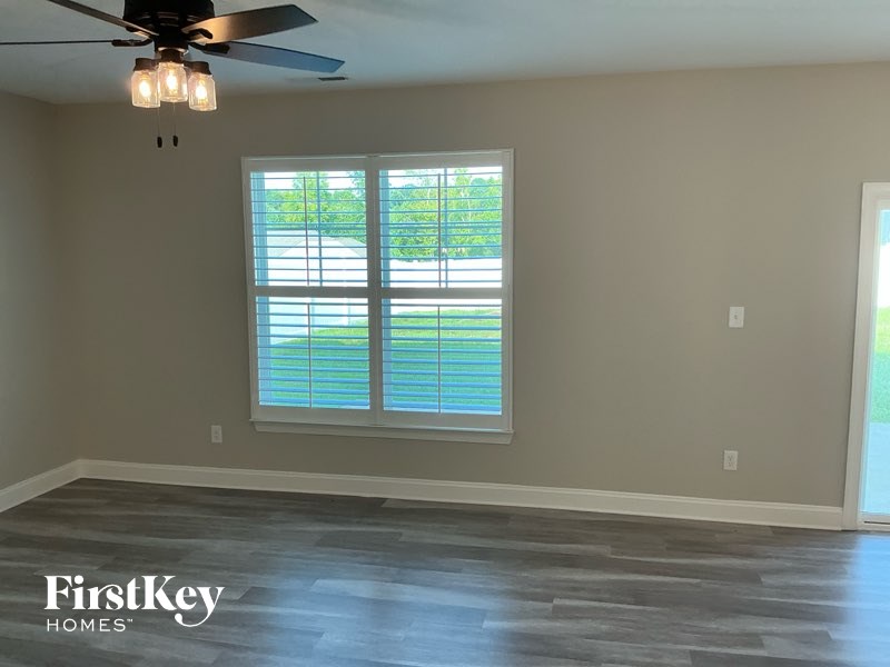 A room with a ceiling fan and a window with blinds.
