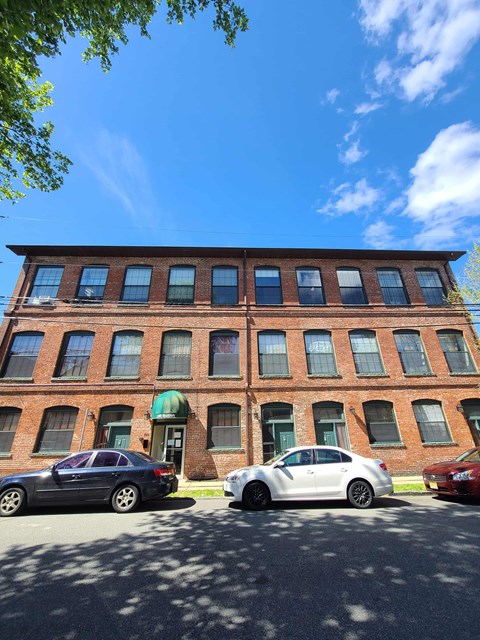 Three cars are parked in front of a red brick building.