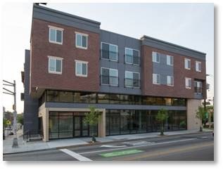 A modern building with a glass entrance and a green crosswalk in front.