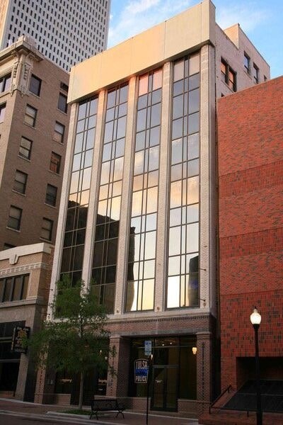A tall building with a red brick wall and a glass window.