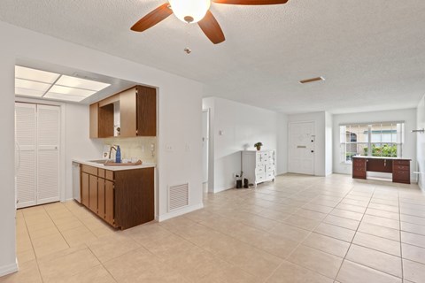 A spacious room with a kitchenette and a ceiling fan.