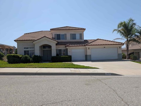 A house with a red tile roof and a driveway in front.