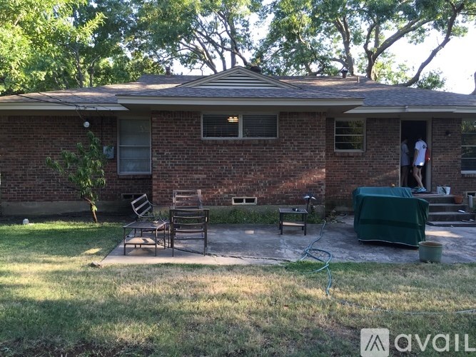 A house with a green lawn and a patio with chairs.