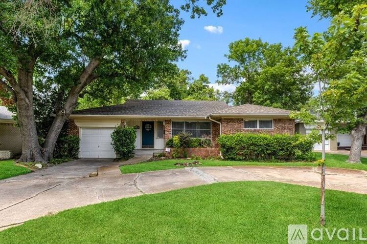 A house with a green lawn and trees in front.