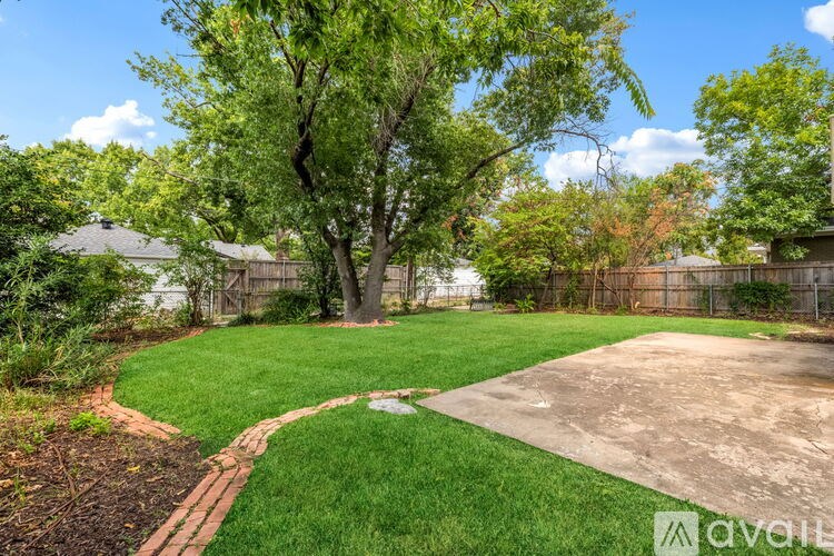 A backyard with a concrete patio and a green lawn.