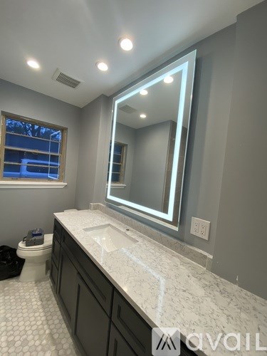 A bathroom with a marble countertop and a large mirror.