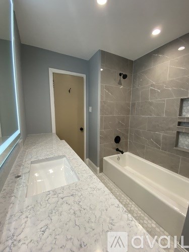 A bathroom with a marble floor and a bathtub.