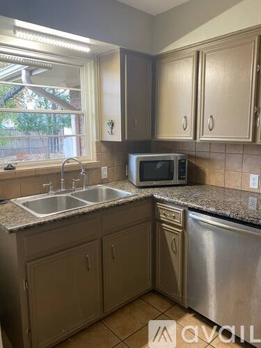 A kitchen with a sink, microwave, and cabinets.