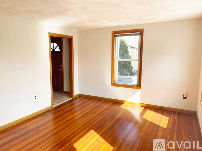 A room with wooden floors and a window with a view of trees outside.