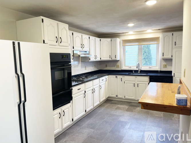 A kitchen with white cabinets and black appliances.