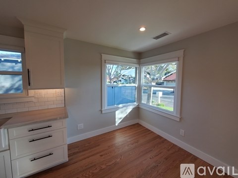 A kitchen with white cabinets and a window overlooking a street.