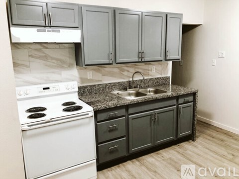 A kitchen with a white stove and black cabinets.