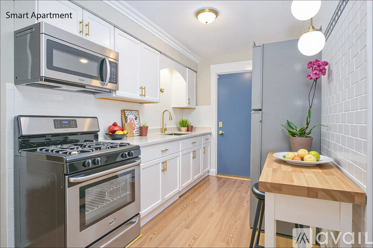 A modern kitchen with a stove, oven, microwave, and a table with fruit on it.