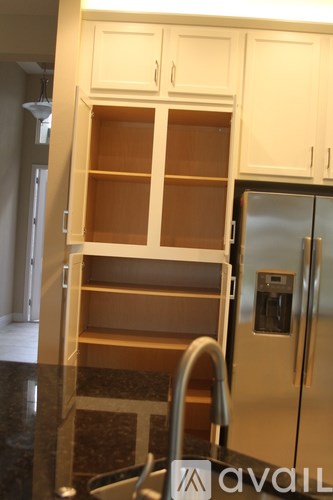A kitchen with a black granite counter top and a stainless steel refrigerator.