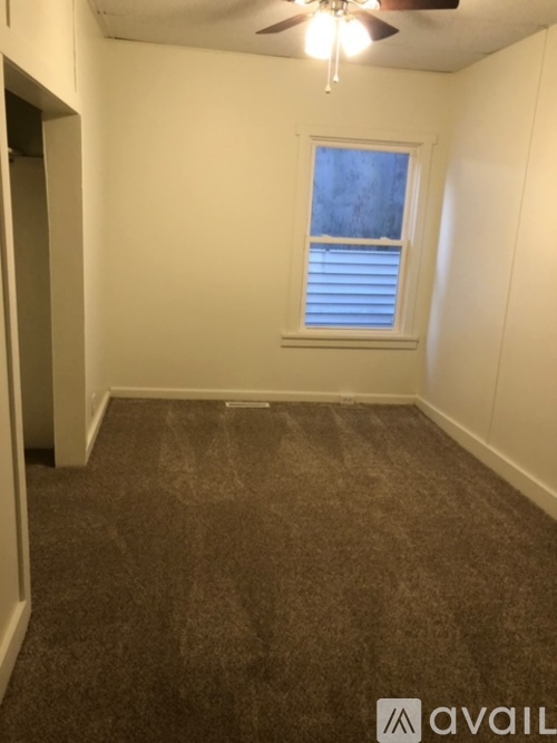 A room with a ceiling fan and carpeted floor.