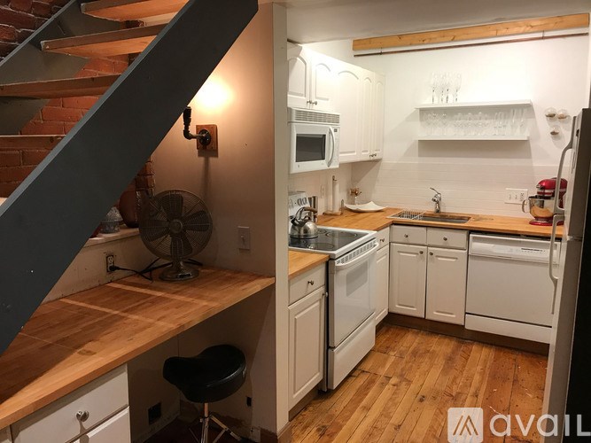 A kitchen with a staircase on the left side.