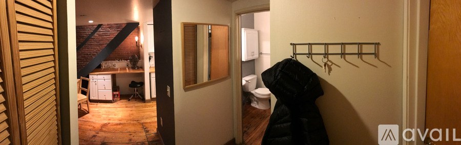 A hallway with a coat hanging on a coat rack.
