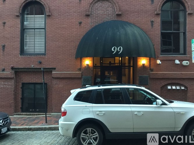 A white car is parked in front of a building with a black awning.