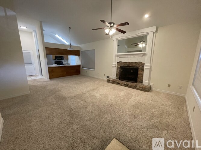 A living room with a fireplace and a ceiling fan.