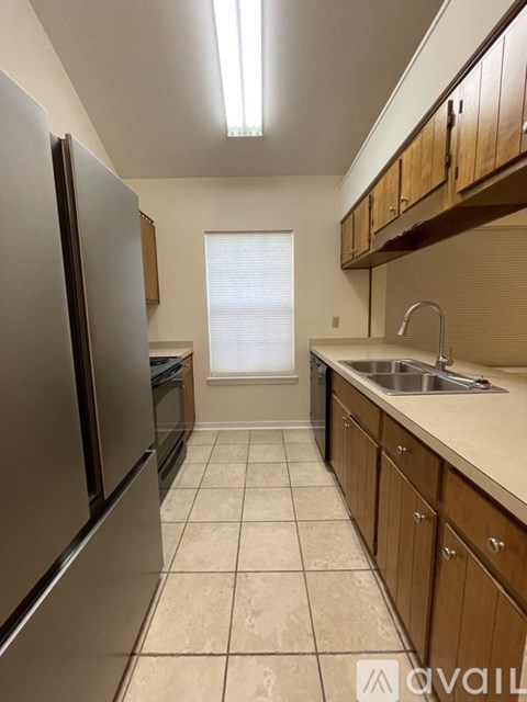 A kitchen with a stainless steel refrigerator and wooden cabinets.