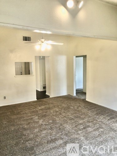 A room with a carpeted floor and a ceiling fan.