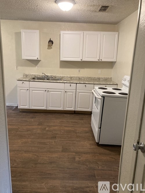 A kitchen with white cabinets and a white stove.