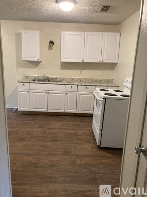 A kitchen with white cabinets and a white stove.
