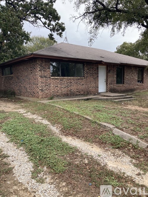 A small house with a white door and windows surrounded by a grassy area.