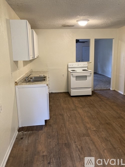 A kitchen with white appliances and wooden floors.