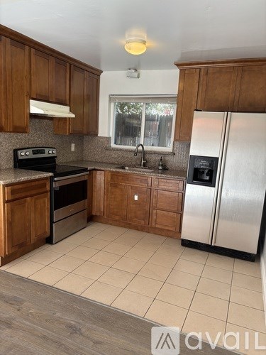 A kitchen with wooden cabinets and a stainless steel refrigerator.