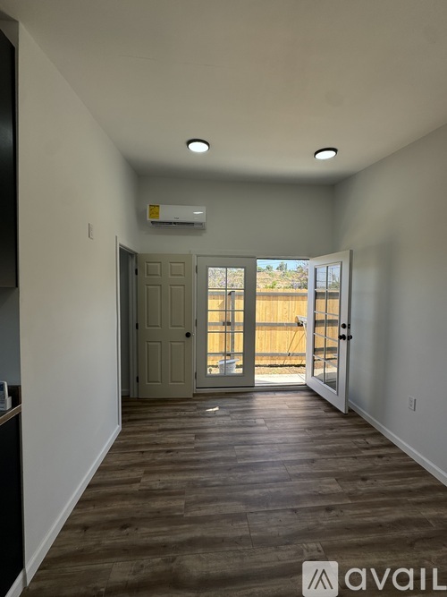 A room with a wooden floor and a sliding glass door leading to a balcony.
