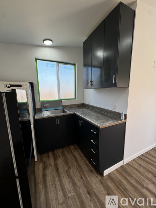 A kitchen with black cabinets and a refrigerator.
