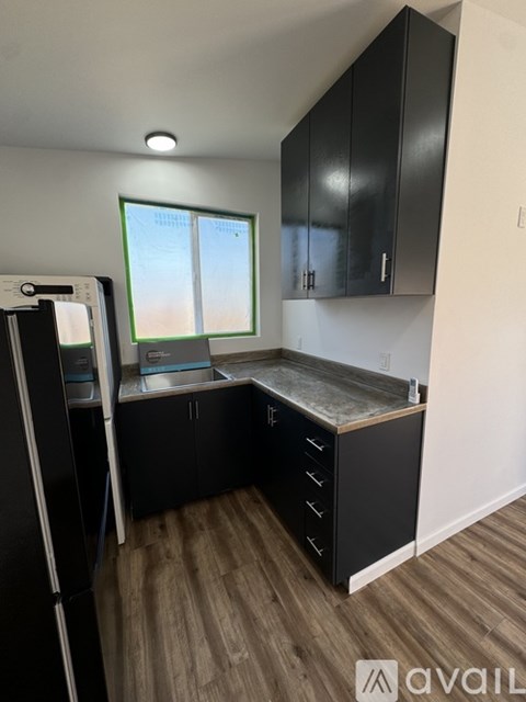 A kitchen with black cabinets and a refrigerator.