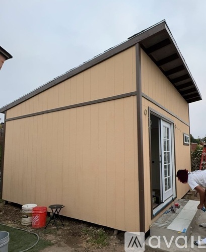 A man is painting the exterior of a beige house.