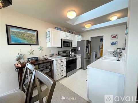 A kitchen with white appliances and a dining table with chairs.