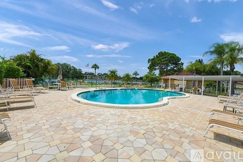 A pool surrounded by sun loungers and a clear blue sky.