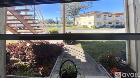 A view from a window looking out to a building and a landscaped garden.