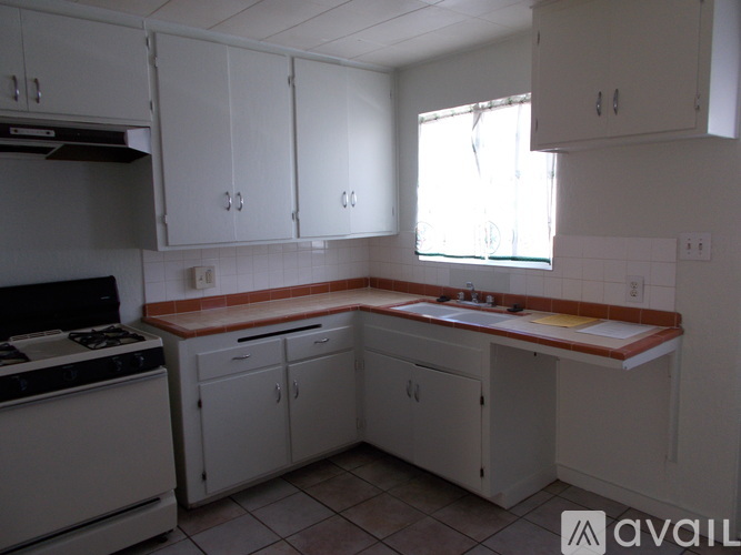 A kitchen with white cabinets and a stove top oven.