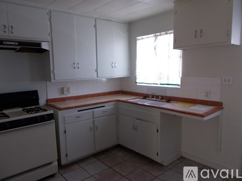 A kitchen with white cabinets and a stove top oven.