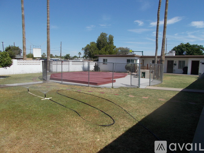 A tennis court surrounded by a fence and a building in the background.
