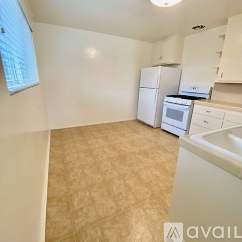 A kitchen with white appliances and beige tiled flooring.