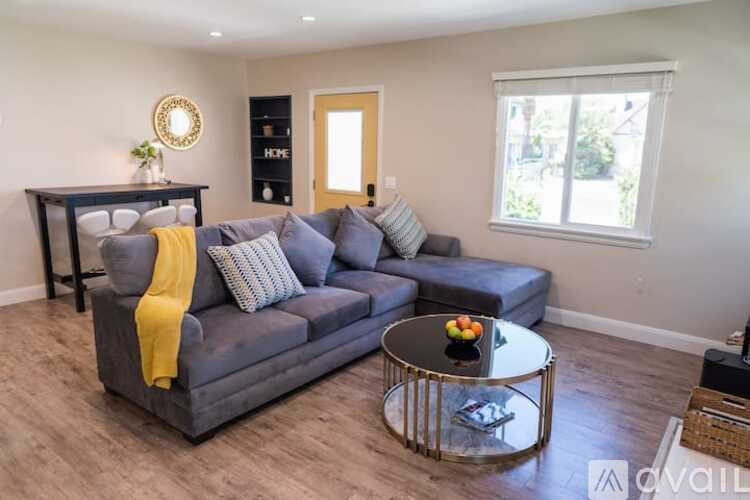 A living room with a grey couch, a yellow throw, and a coffee table.