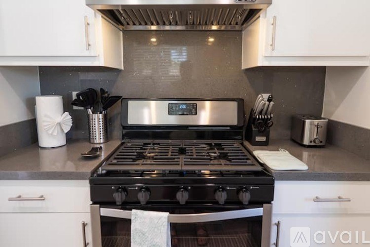 A modern kitchen with a black stove top oven and white cabinets.